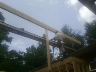 Carpenter setting a ridge beam over a new addition frame — Ice Dam Removal by Roofing Brothers in Sealy