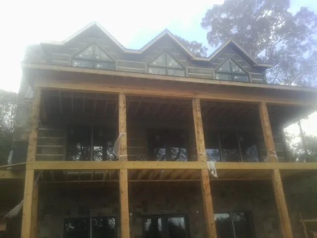 Dormers and porch framing on a large log home under construction — Roof Coating work by our crew in Sealy