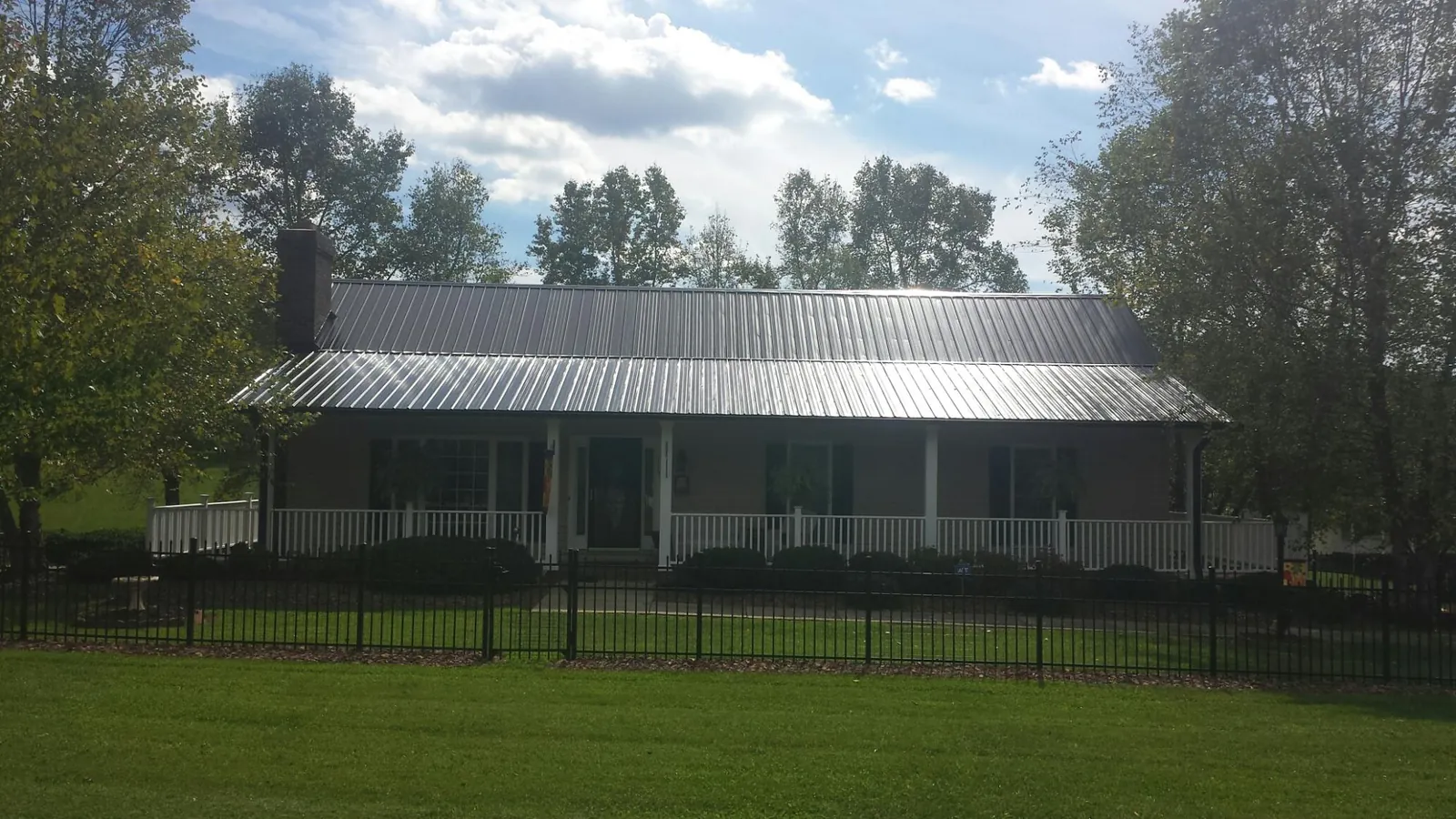 Gray metal roof on a brick ranch with a full width front porch — Gutter Guard Installation work by our crew in Sealy