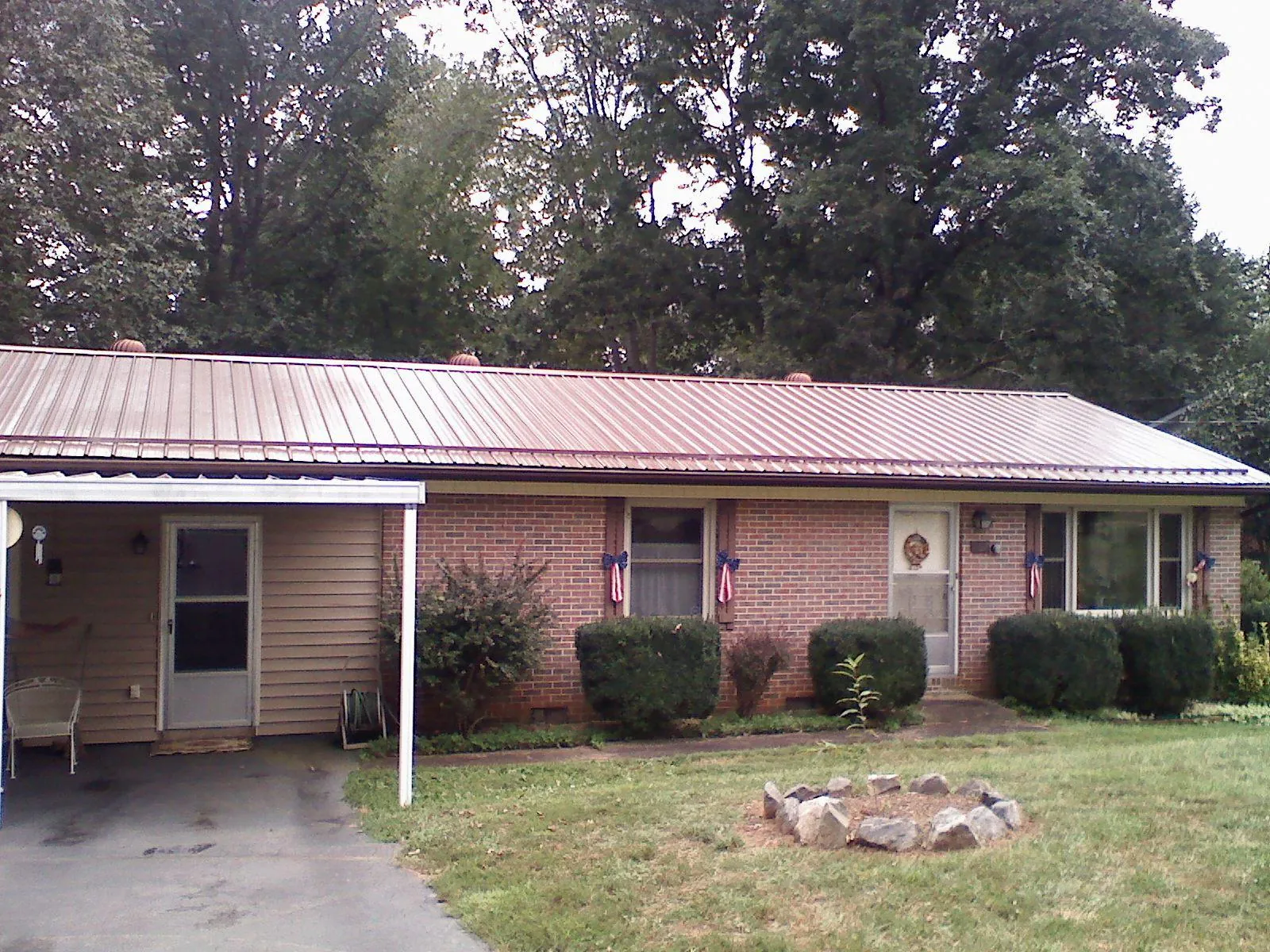 Bronze metal roof and carport on a brick ranch home — Roof Repair work by our crew in Sealy