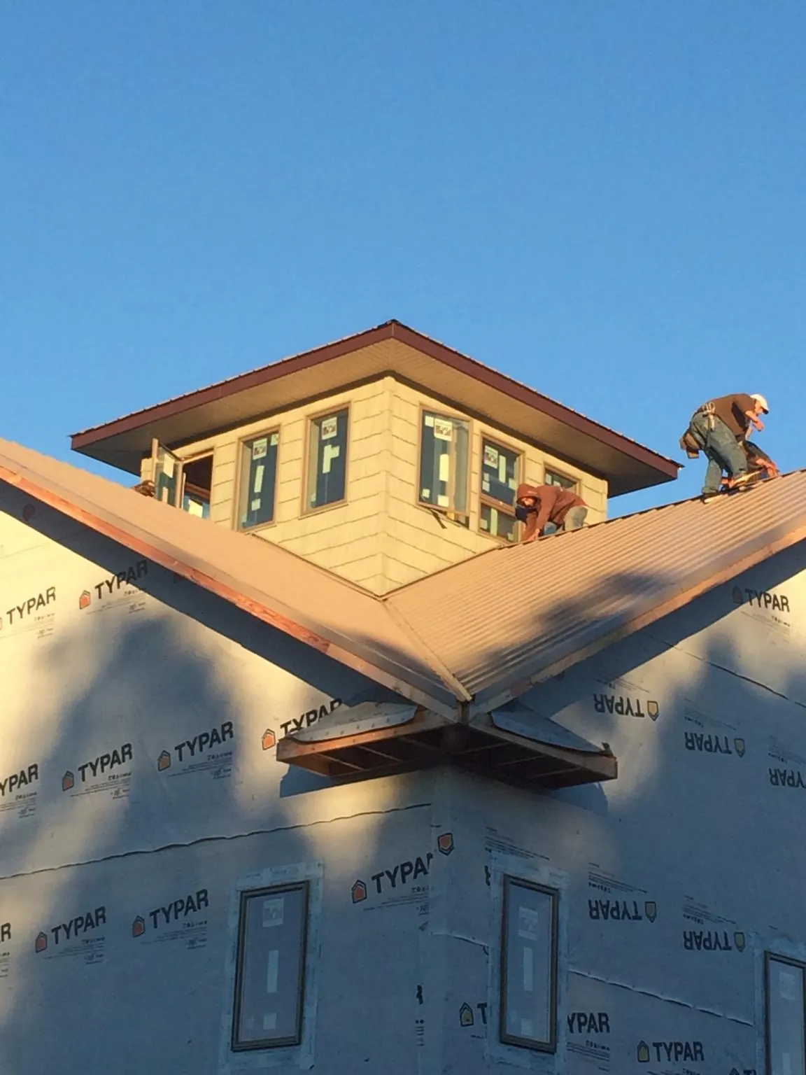 Roofers working around a rooftop cupola on a new metal roof at sunset — Roof Waterproofing in Sealy by Roofing Brothers